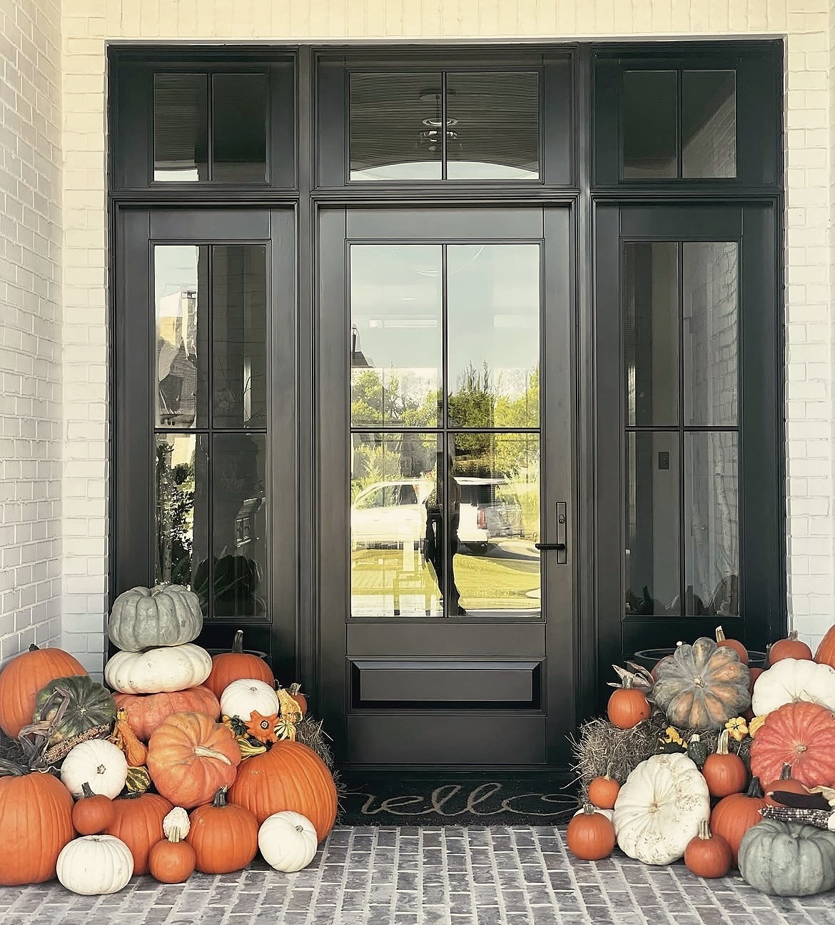 Autumn Essentials pumpkin porch display on modern white brick home